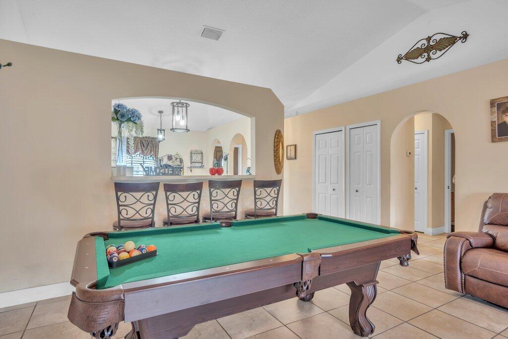 A game room features a pool table, four bar stools, and a kitchen pass-through window — 3011 NW 33rd Avenue, Okeechobee FL 34972, OKEECHOBEE, FL