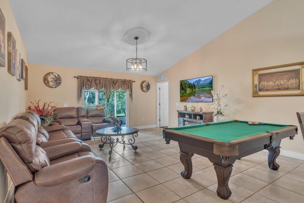 A living room featuring a brown leather sofa, a pool table, and tile flooring — 3011 NW 33rd Avenue, Okeechobee FL 34972, OKEECHOBEE, FL
