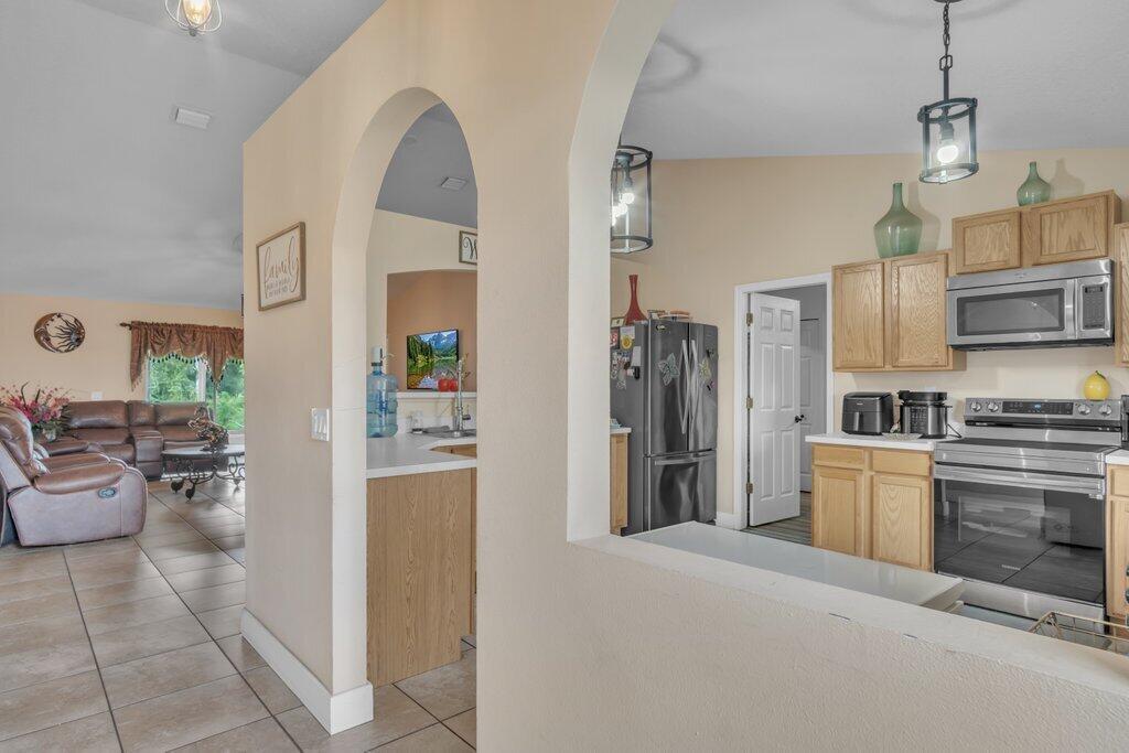 A view through an arched doorway into a living room and an adjacent kitchen — 3011 NW 33rd Avenue, Okeechobee FL 34972, OKEECHOBEE, FL