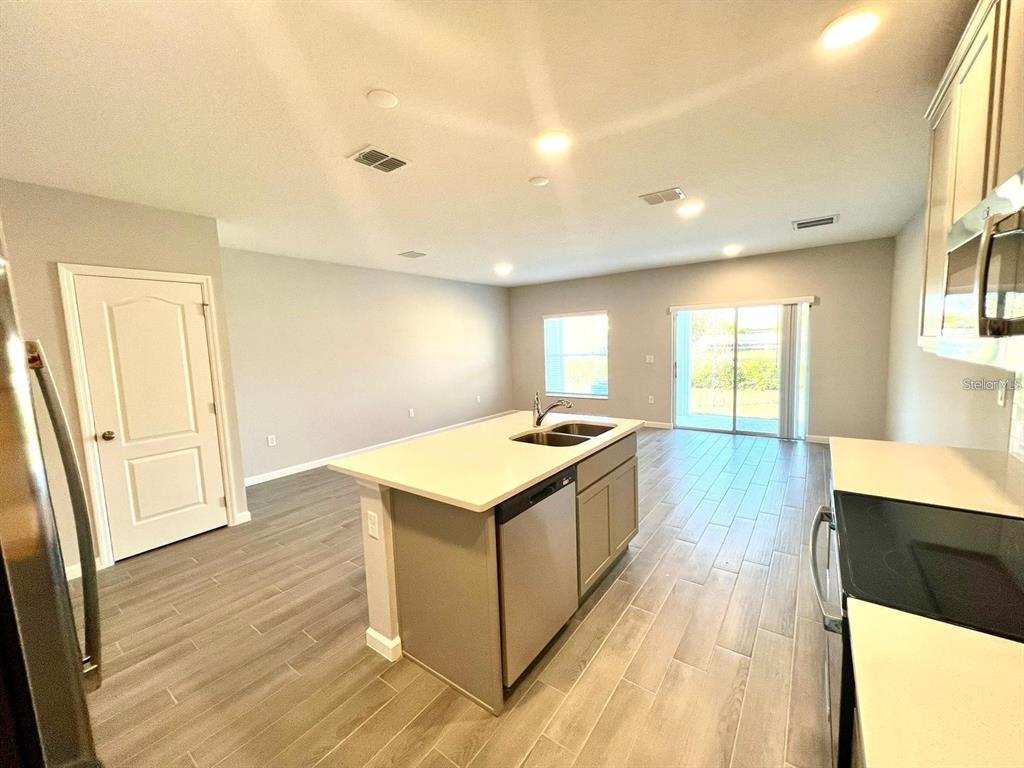 A kitchen with a central island and light-colored cabinets opens into a spacious living area — 2774 NARCOOSSEE COMMONS WAY, ST CLOUD, FL