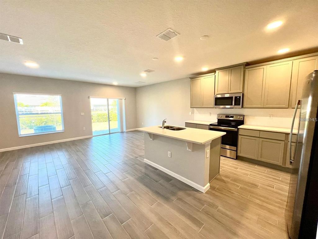 A kitchen with light gray cabinets, a central island, and wood-look tile flooring — 2774 NARCOOSSEE COMMONS WAY, ST CLOUD, FL