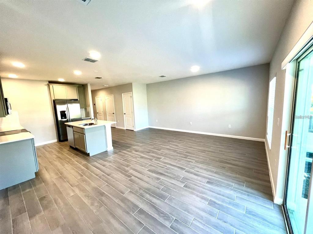 An open-concept kitchen and living area with light gray tile flooring and white cabinetry — 2774 NARCOOSSEE COMMONS WAY, ST CLOUD, FL