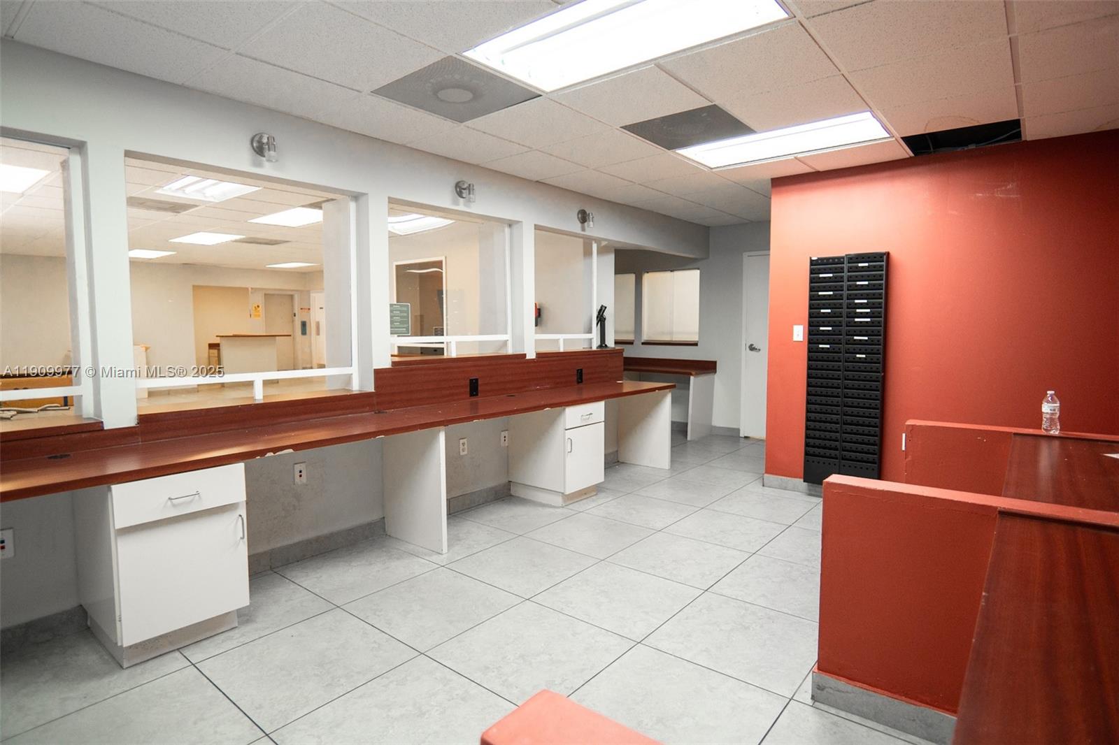 An office interior features a long wooden counter with white cabinets and glass partitions — 1901 SW 1st St, Miami FL 33135, MIAMI, FL