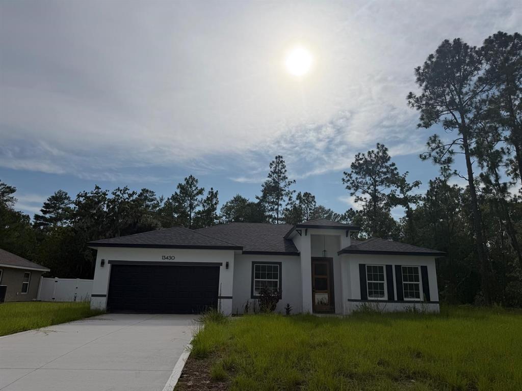 A single-story house with a white exterior, black trim, and a two-car garage — 13430 SW 88TH TERRACE, DUNNELLON, FL