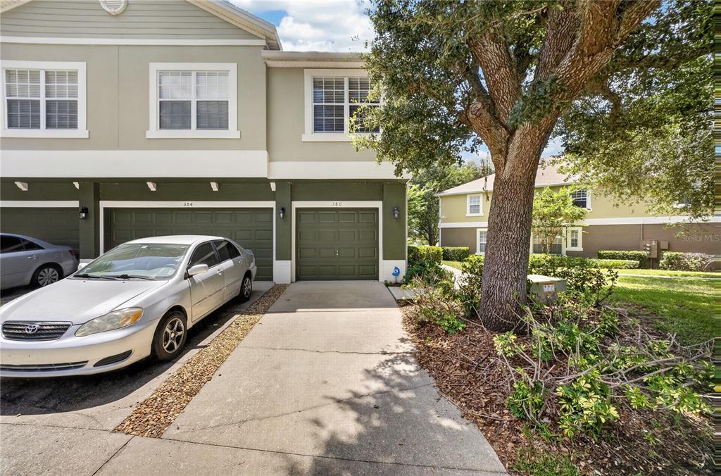 A silver sedan is parked in the driveway of a two-story townhouse with green garages — 380 ASHLEY BROOKE COURT UNIT C, APOPKA, FL