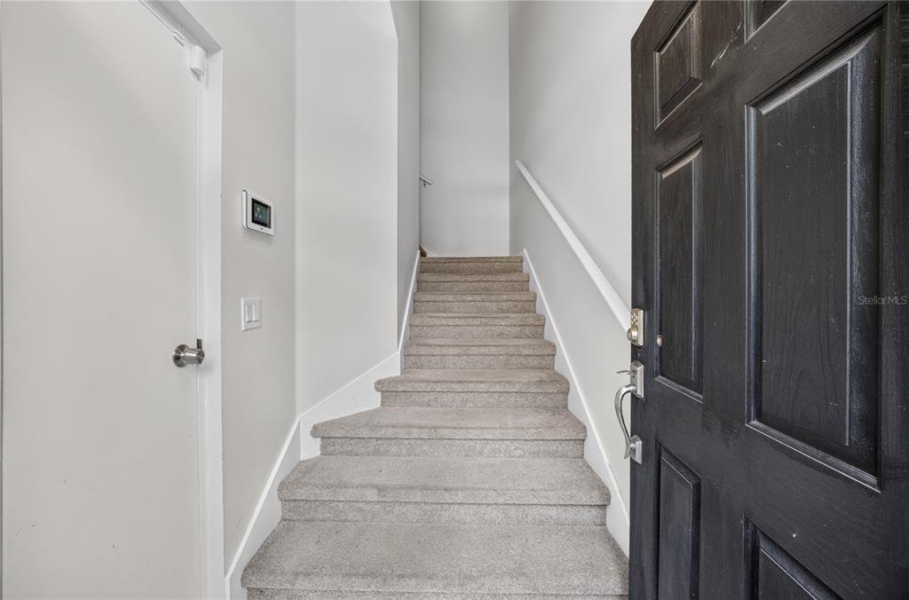A carpeted staircase leads upward from a doorway with a dark wooden door — 380 ASHLEY BROOKE COURT UNIT C, APOPKA, FL
