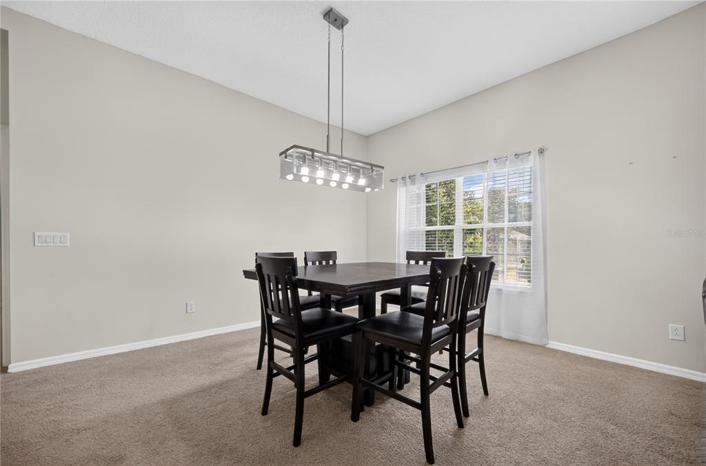 A dining room features a dark wood table with six chairs under a rectangular pendant light — 380 ASHLEY BROOKE COURT UNIT C, APOPKA, FL