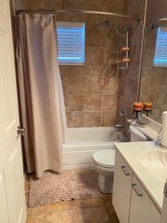 A bathroom features a shower-tub combination with tan tile walls and a beige shower curtain — 20020 NE 6th Court, Miami FL 33179, MIAMI, FL