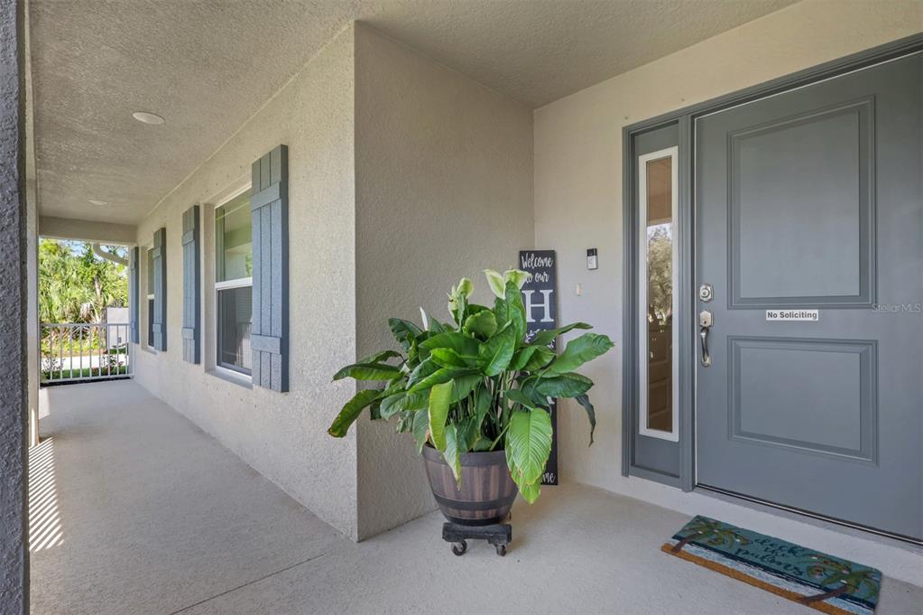 A covered front porch features a gray door, a potted plant, and blue shutters — 4597 KENVIL DRIVE, NORTH PORT, FL
