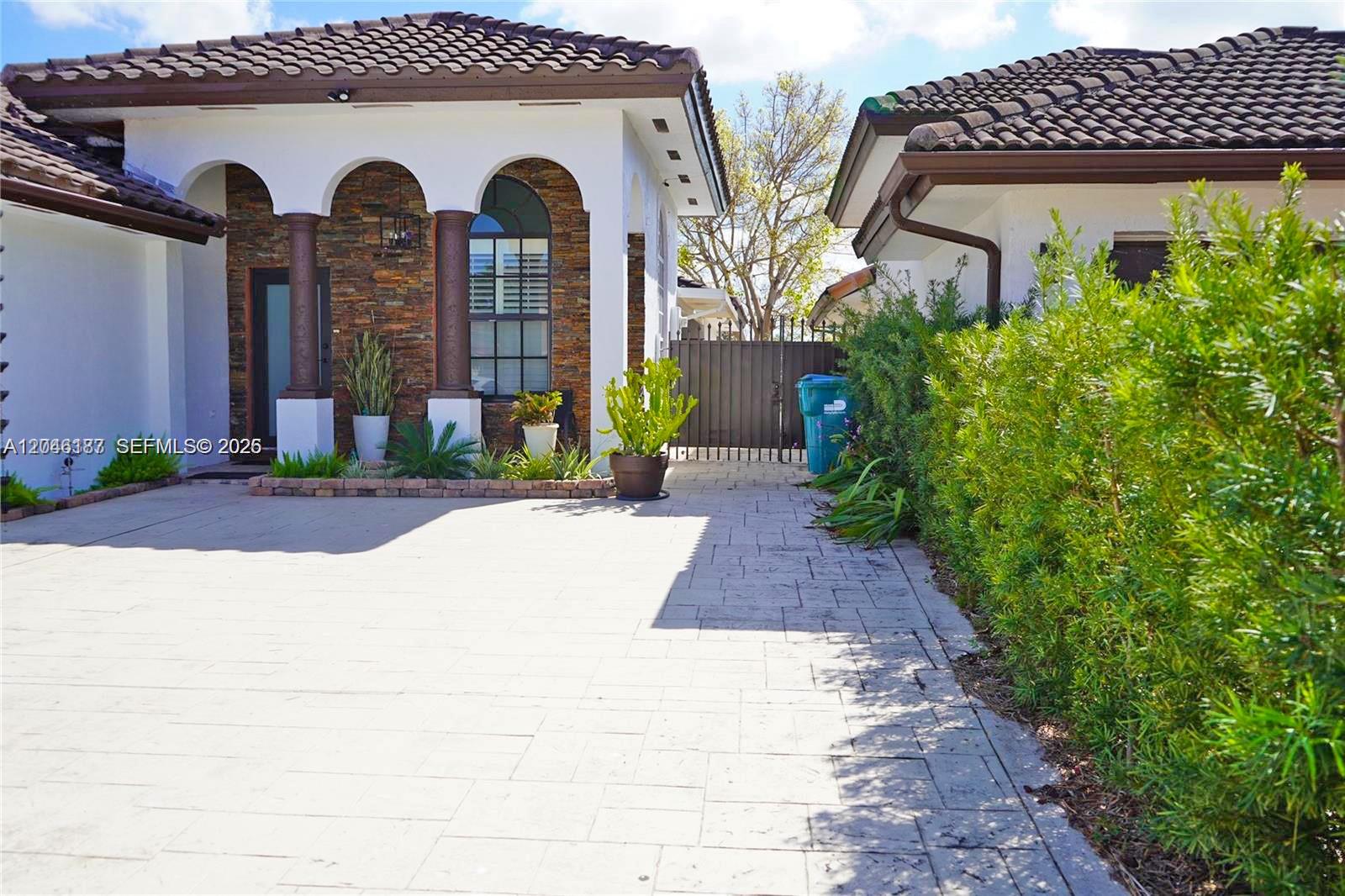 A paved driveway leads to a house entrance featuring stone accents and arched columns — 3461 SW 154th Ct, Miami FL 33185, MIAMI, FL
