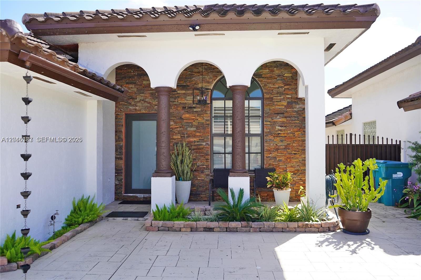 The exterior of a house features a stone-clad entryway with arched openings and columns — 3461 SW 154th Ct, Miami FL 33185, MIAMI, FL
