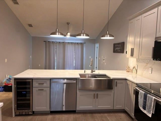A kitchen features white cabinets, a farmhouse sink, stainless steel appliances, and a quartz countertop — 232 CRESTWOOD PASS, DAVENPORT, FL