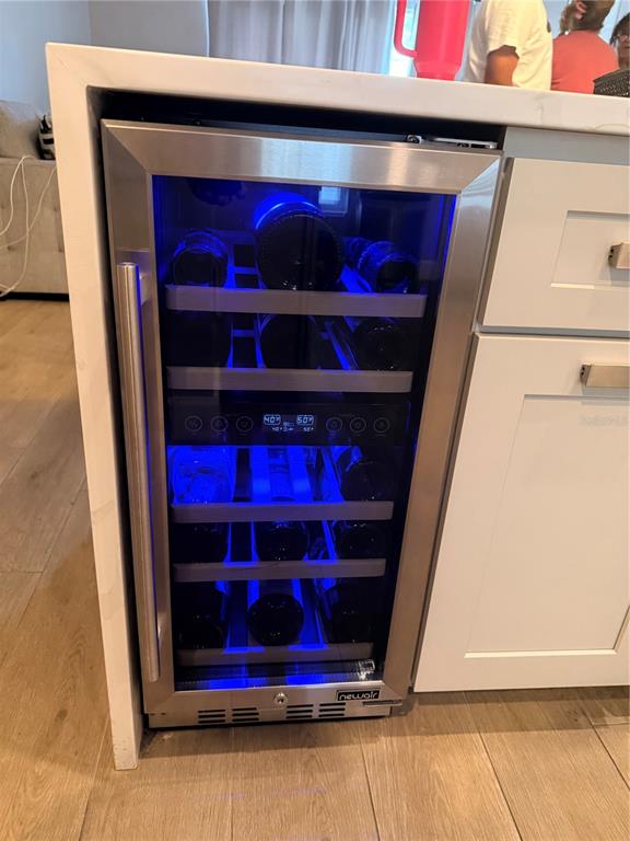 A stainless steel wine refrigerator is built into a white kitchen island cabinet — 232 CRESTWOOD PASS, DAVENPORT, FL