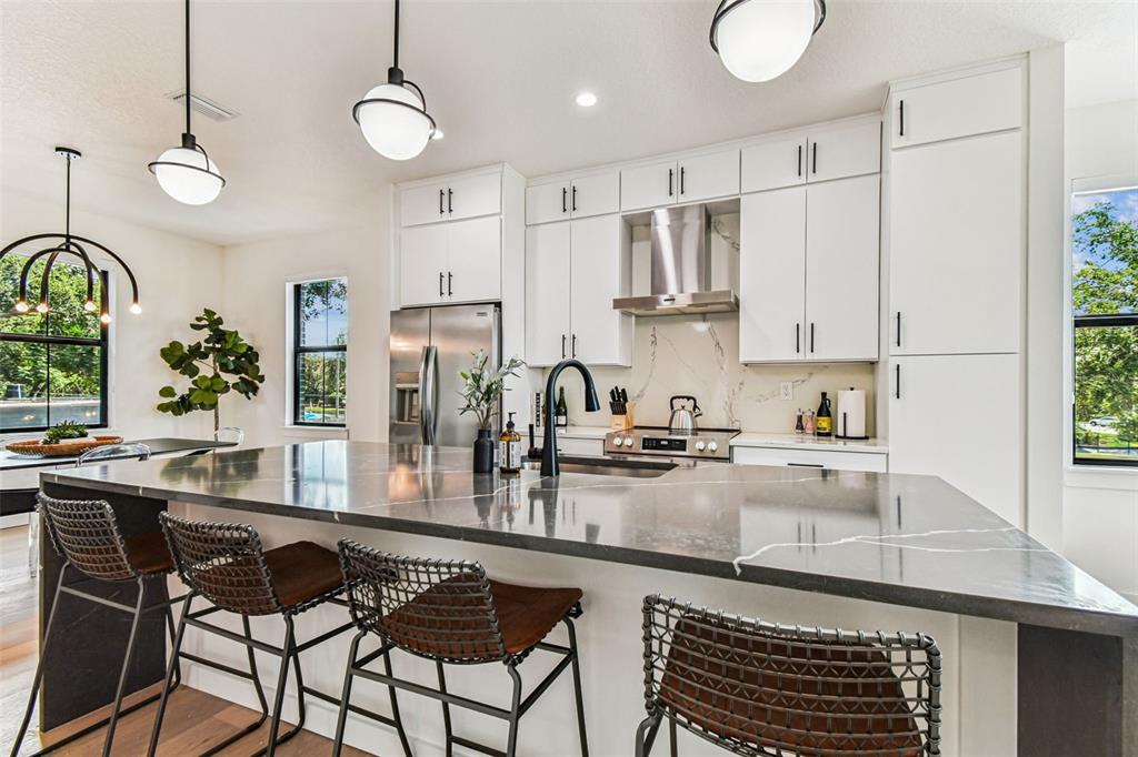 A modern kitchen features white cabinetry, a dark stone island, and bar stool seating — 1218 E KAY STREET UNIT 27, TAMPA, FL