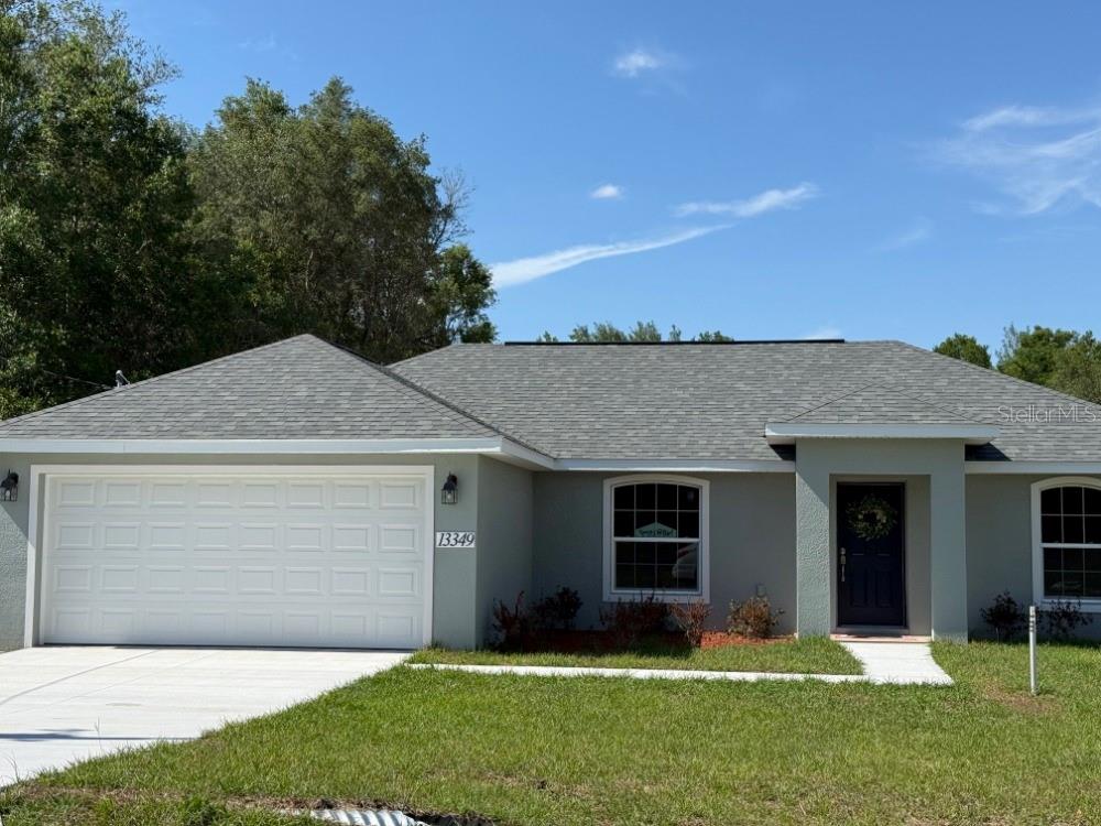 A single-story house with a gray exterior, a white garage door, and a dark front door — 13337 SW 112 STREET, DUNNELLON, FL