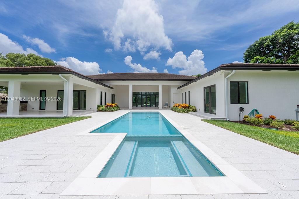 A long rectangular swimming pool sits in the center of a white-tiled patio area — 11861 NW 9th St, Plantation FL 33325, PLANTATION, FL