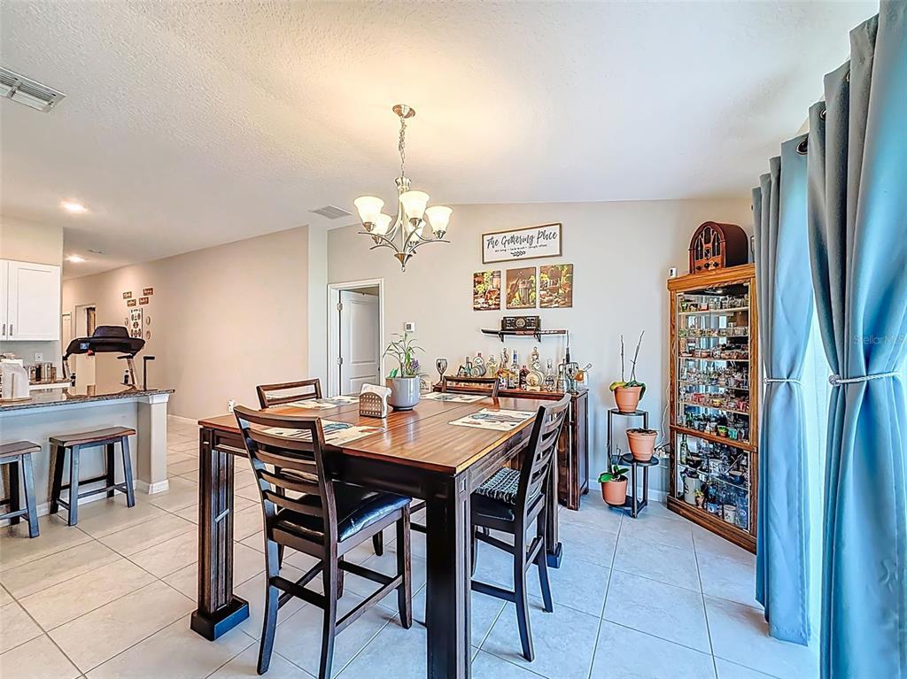 A dining room with a wooden table, chairs, a display cabinet, and tile flooring — 13360 WILLOW BLUESTAR LOOP, RIVERVIEW, FL