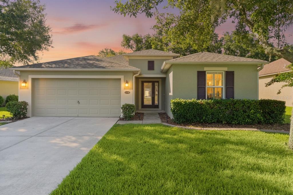 A single-story house with a light green exterior, a two-car garage, and a concrete driveway — 4358 ANTIETAM CREEK TRAIL, LEESBURG, FL