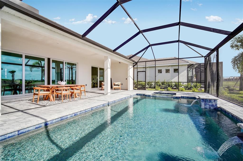 A screened-in patio features a swimming pool with a spa and an outdoor dining area — 18939 CHERRYSTONE WAY, LAKEWOOD RANCH, FL