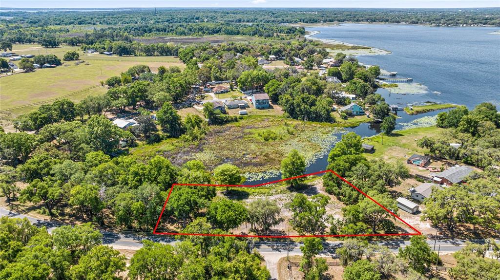 An aerial view shows a vacant, tree-covered lot outlined in red next to a lake — 0 SE 110TH STREET ROAD, BELLEVIEW, FL
