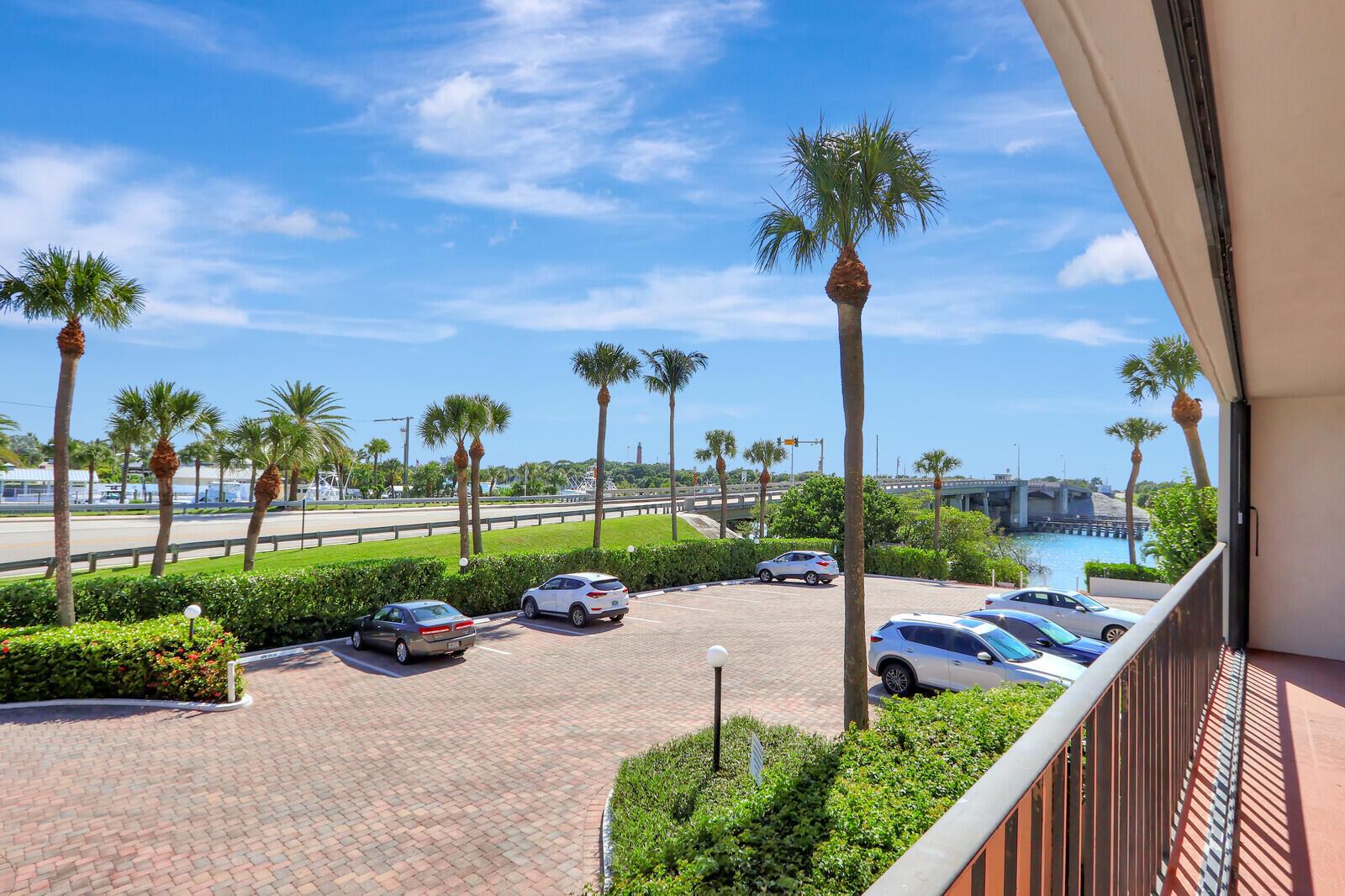 A view from a balcony overlooking a parking lot, palm trees, and a distant bridge — 225 Beach Road # 204, Tequesta FL 33469, TEQUESTA, FL