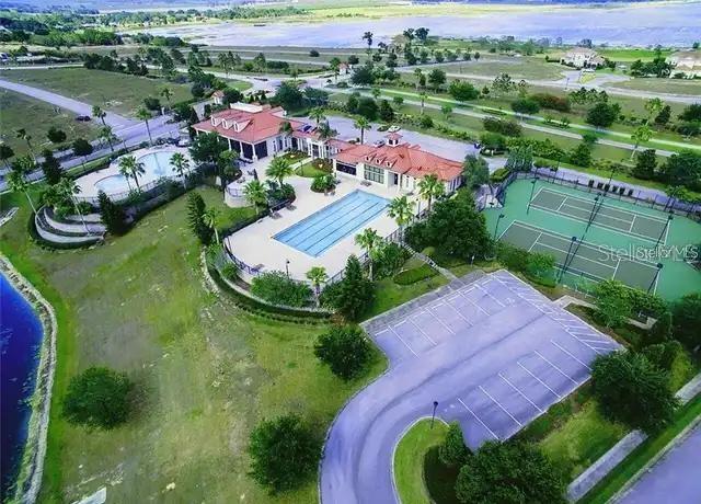 An aerial view of a community clubhouse featuring a swimming pool, tennis courts, and parking — 211 BLAZING STAR AVENUE, LAKE ALFRED, FL