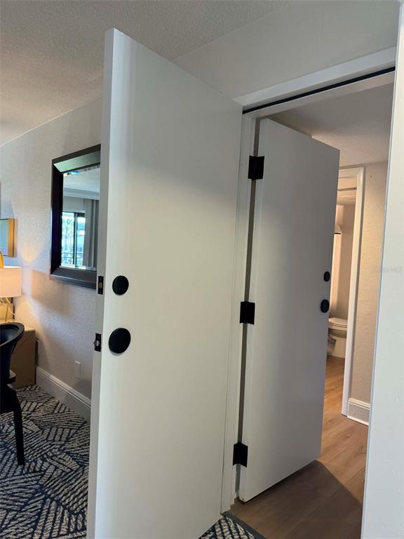 A white door stands open, revealing a bathroom with wood-look flooring and a toilet — 4762 FOX HUNT DRIVE UNIT A304 & A302, WESLEY CHAPEL, FL