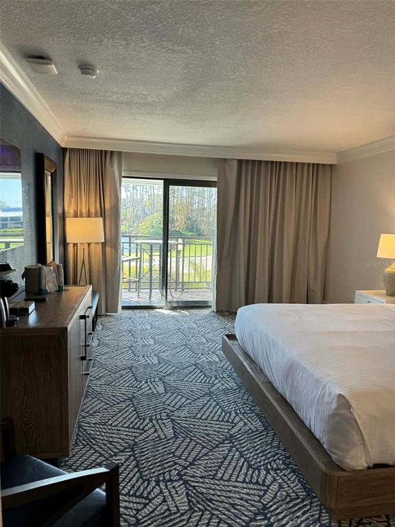 A hotel room features a bed, a wooden dresser, patterned carpet, and a sliding glass door — 4762 FOX HUNT DRIVE UNIT A304 & A302, WESLEY CHAPEL, FL
