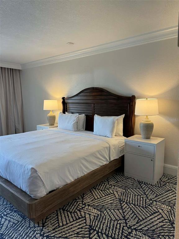 A bedroom features a wooden bed frame, two nightstands with lamps, and patterned carpet — 4762 FOX HUNT DRIVE UNIT A304 & A302, WESLEY CHAPEL, FL