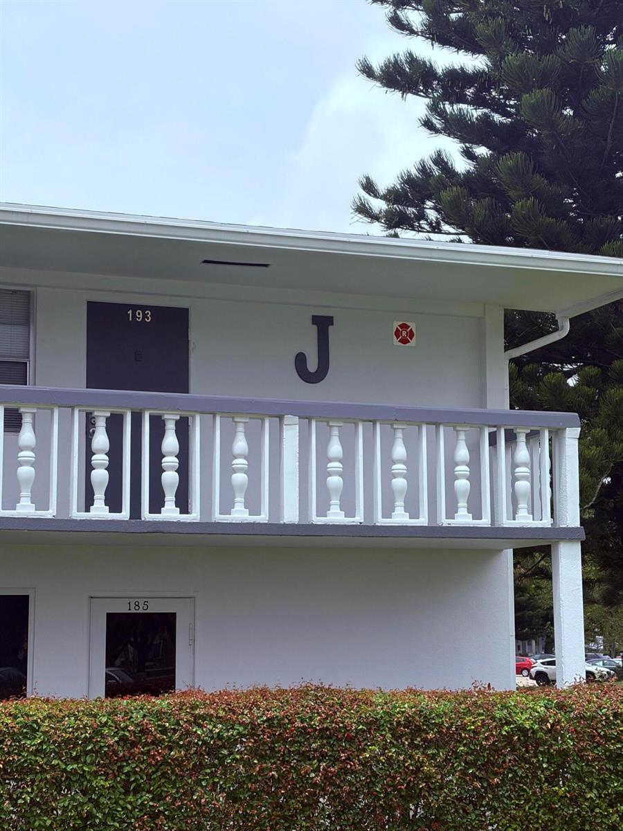 The exterior of a two-story building features a white balcony with balusters and unit numbers — 193 Prescott J # J, Deerfield Beach FL 33442, DEERFIELD BEACH, FL