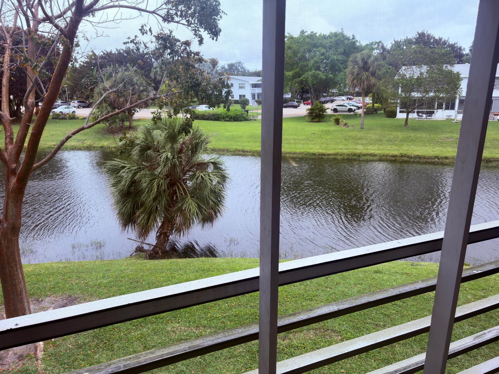 A view of a pond and green lawn from behind a screened-in porch — 193 Prescott J # J, Deerfield Beach FL 33442, DEERFIELD BEACH, FL