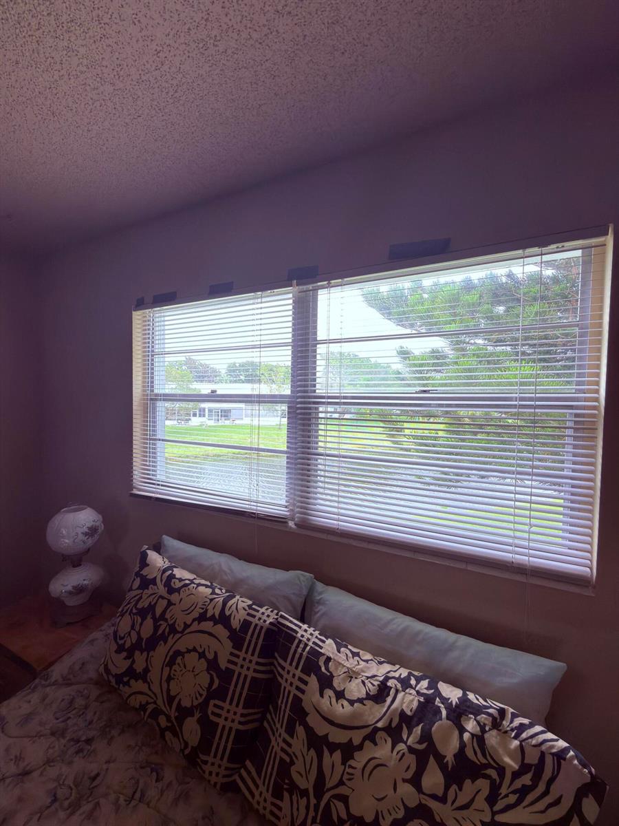 A bedroom features a window with horizontal blinds overlooking a grassy area and trees — 193 Prescott J # J, Deerfield Beach FL 33442, DEERFIELD BEACH, FL
