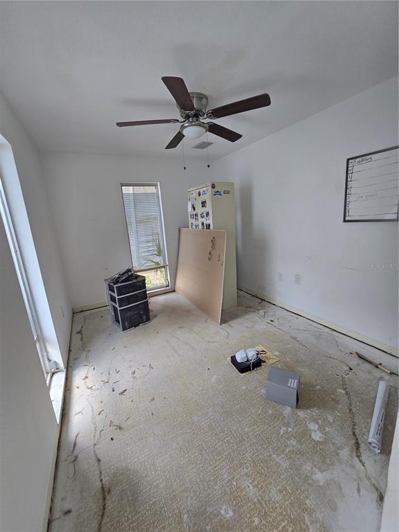 An empty room with white walls, a ceiling fan, and bare concrete subflooring — 908 GRAND CENTRAL STREET, CLEARWATER, FL