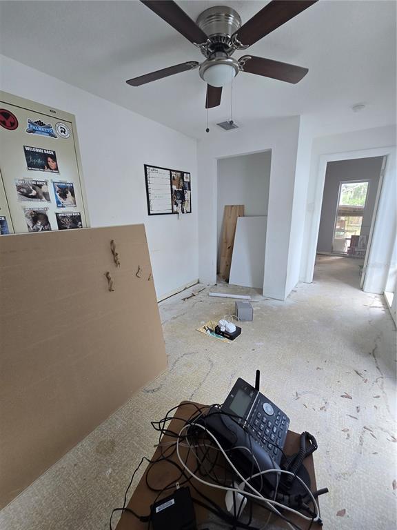 An unfinished room features a ceiling fan, a metal cabinet, and exposed subflooring — 908 GRAND CENTRAL STREET, CLEARWATER, FL