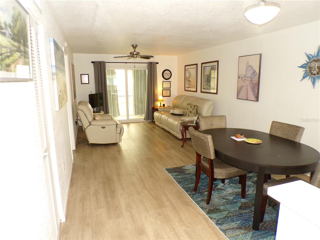 A living and dining area features light wood flooring, a beige sofa, and a table — 649 TAMIAMI TRAIL S UNIT 305, VENICE, FL