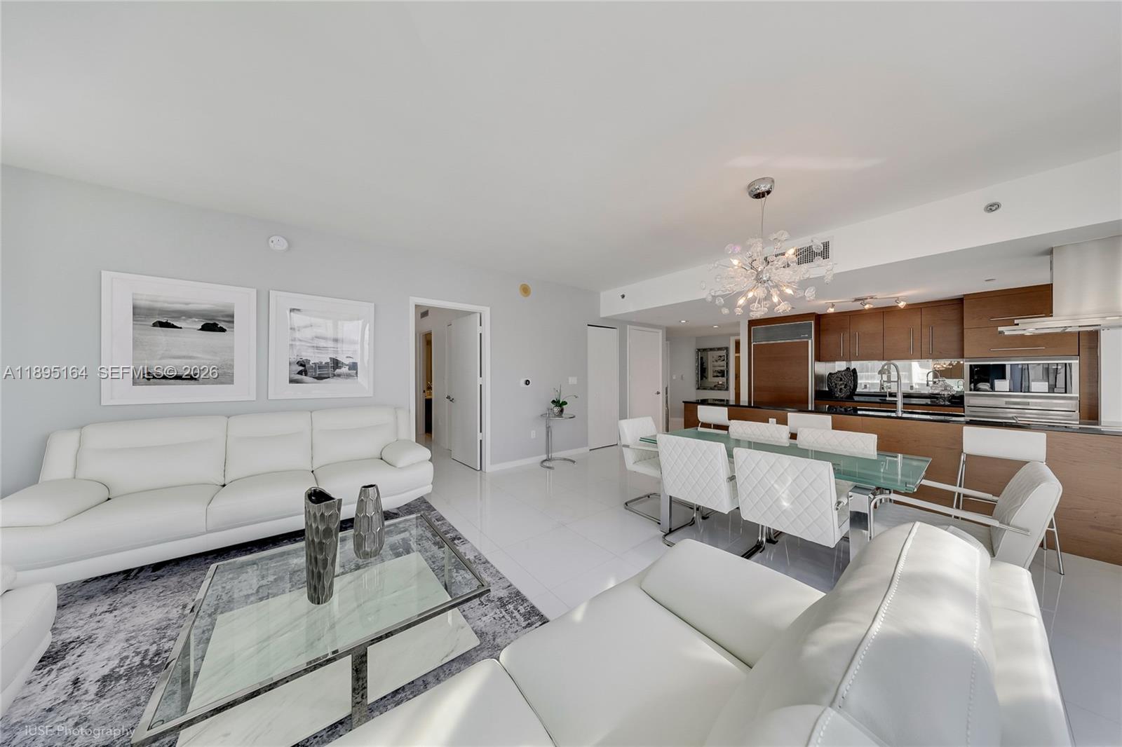 An open-concept living and dining area features white leather furniture, tile flooring, and wood cabinetry — 495 Brickell Ave # 4710, Miami FL 33131, MIAMI, FL