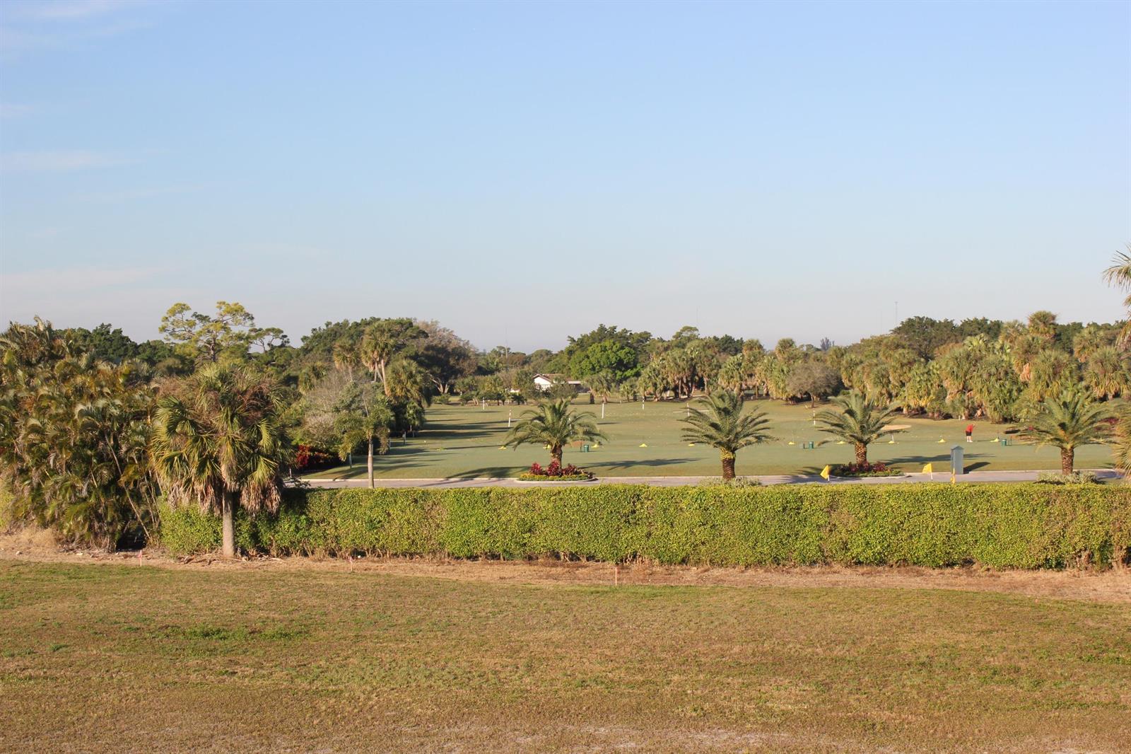 A view of a golf course driving range with palm trees and a manicured hedge — 331 Orange Tree Drive, Atlantis FL 33462, ATLANTIS, FL