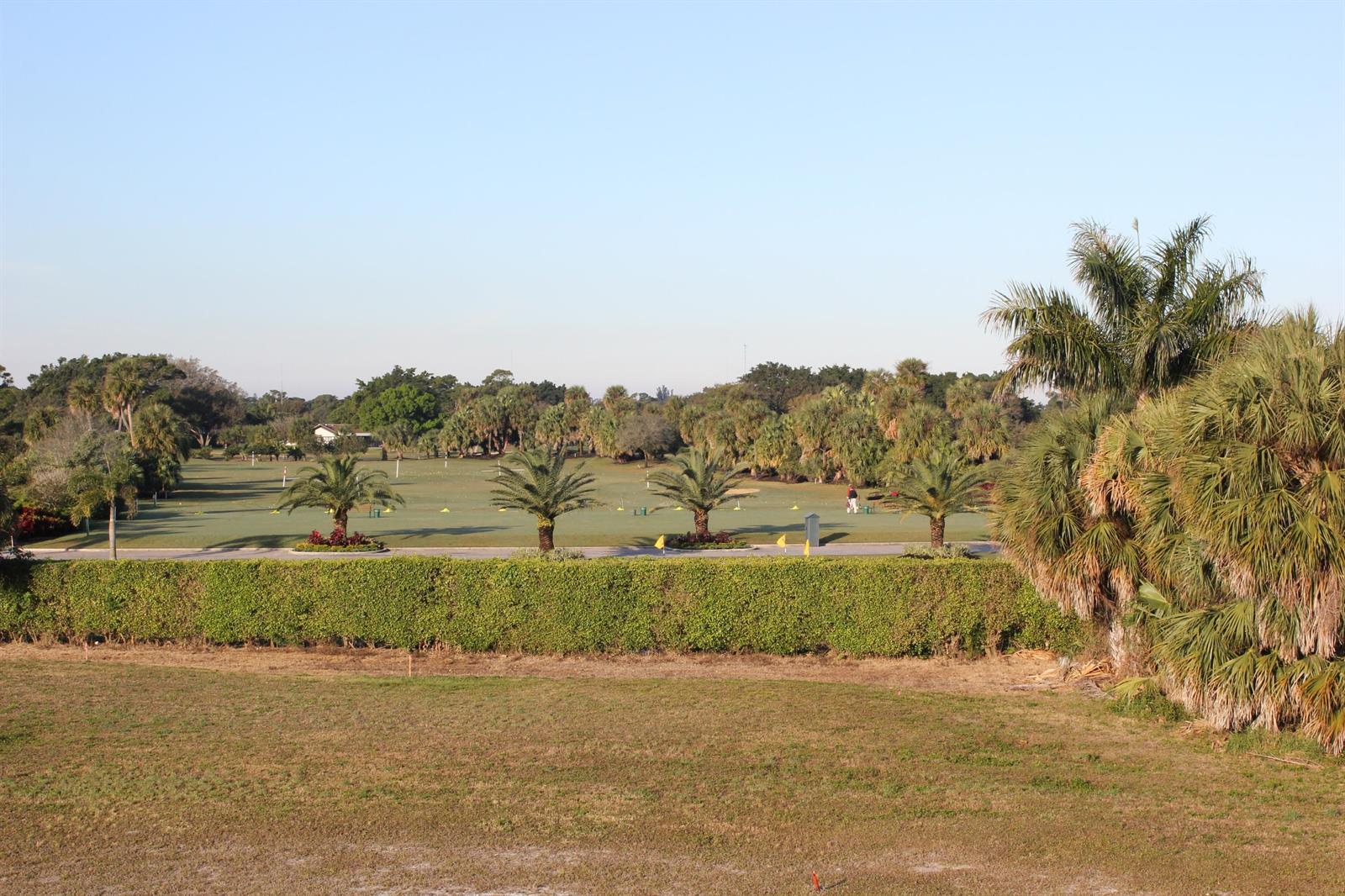 A view of a golf course driving range with palm trees and a manicured hedge — 331 Orange Tree Drive, Atlantis FL 33462, ATLANTIS, FL