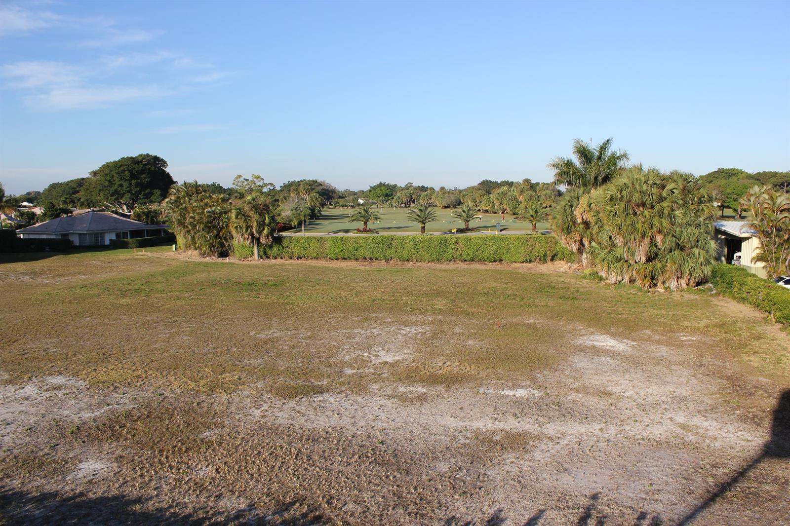 An elevated view of a large, vacant grassy lot overlooking a golf course — 331 Orange Tree Drive, Atlantis FL 33462, ATLANTIS, FL