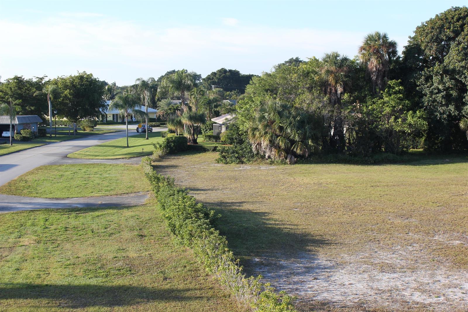 An elevated view of a vacant residential lot bordered by a hedge and mature trees — 331 Orange Tree Drive, Atlantis FL 33462, ATLANTIS, FL
