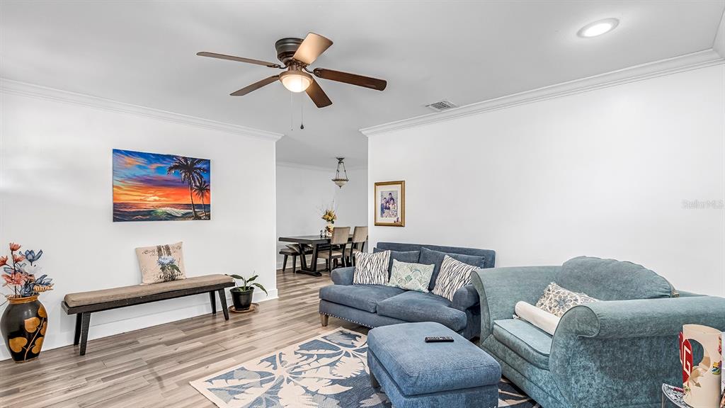A living room with blue sofas, a wooden bench, and a dining area in the background — 2906 FIELDCREST COURT, ORLANDO, FL