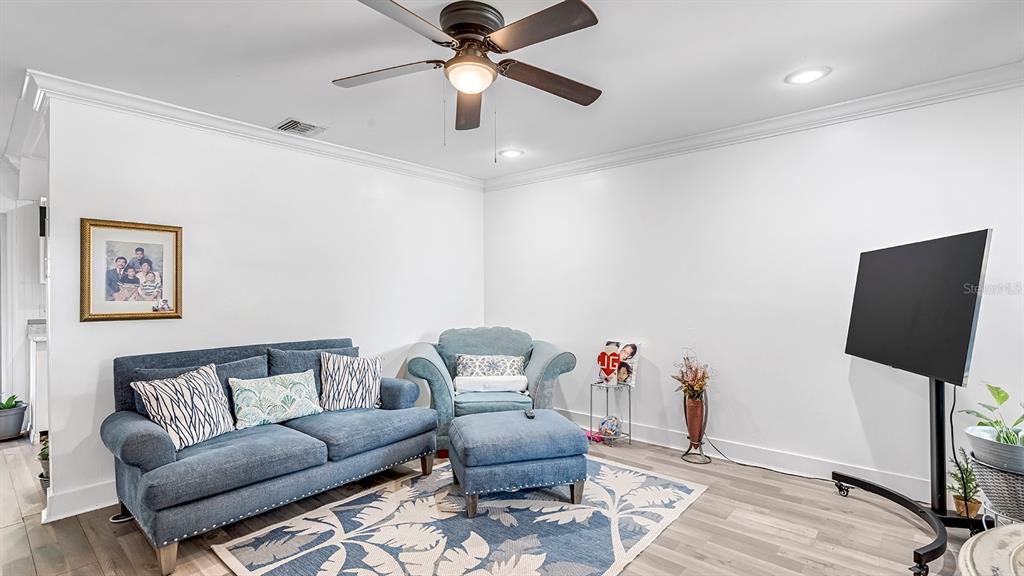 A living room features a blue sofa, matching armchair with ottoman, and a television on a stand — 2906 FIELDCREST COURT, ORLANDO, FL