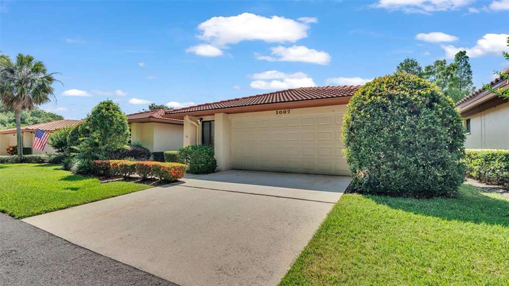 A single-story house with a beige exterior, a two-car garage, and a manicured front lawn — 1007 ROLLING WOODS LANE, LAKELAND, FL