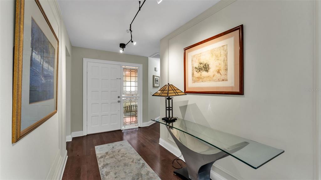 A foyer features dark hardwood floors, a glass console table, and a stained-glass front door — 1007 ROLLING WOODS LANE, LAKELAND, FL