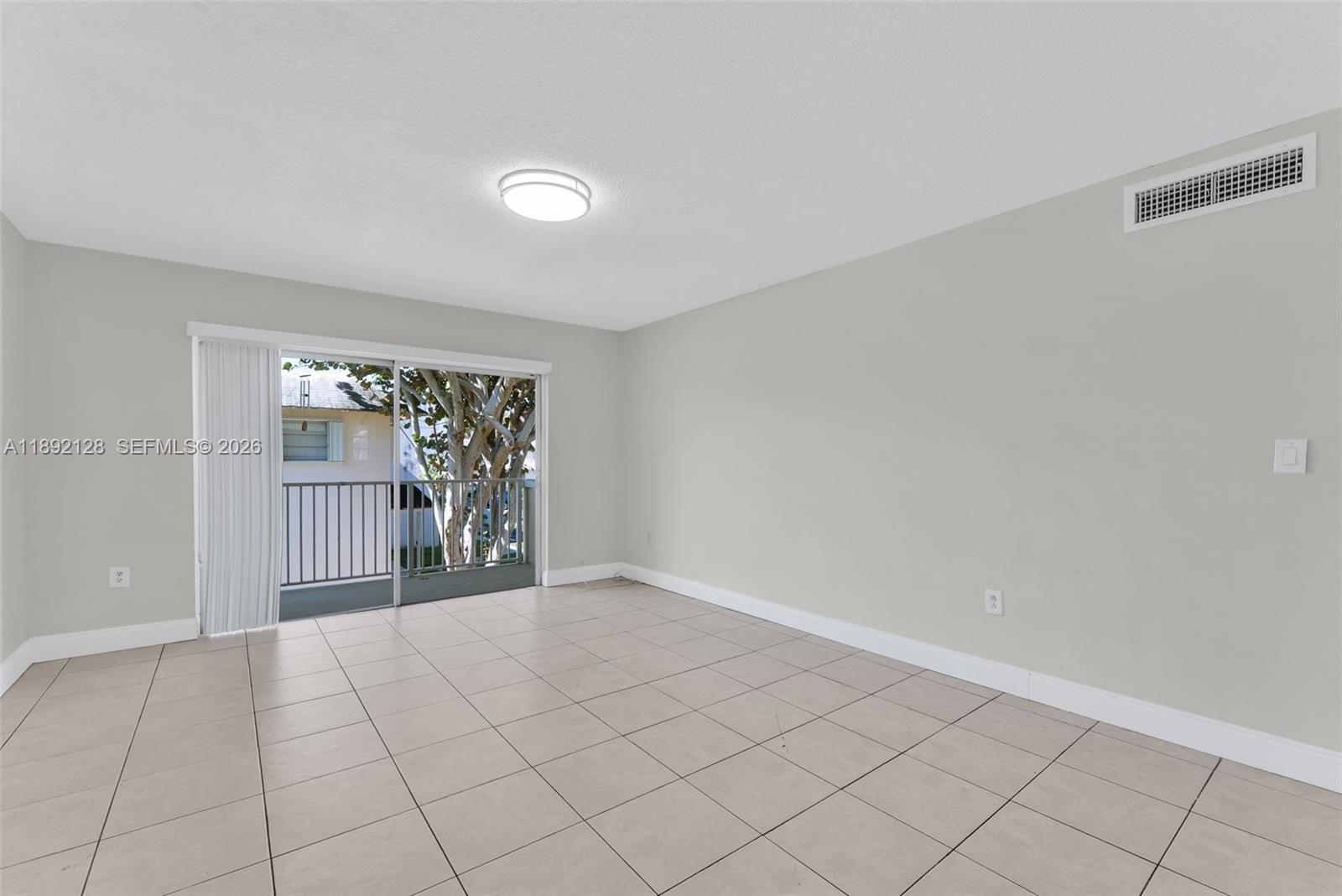 An empty room features light-colored tile flooring, a sliding glass door, and a ceiling light — 7330 SW 82nd St # B218, Miami FL 33143, MIAMI, FL