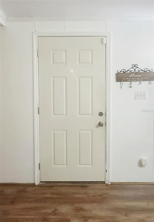 A white six-panel door is centered on a plain wall above wood-look flooring — 4030 NE 212TH TERRACE, WILLISTON, FL