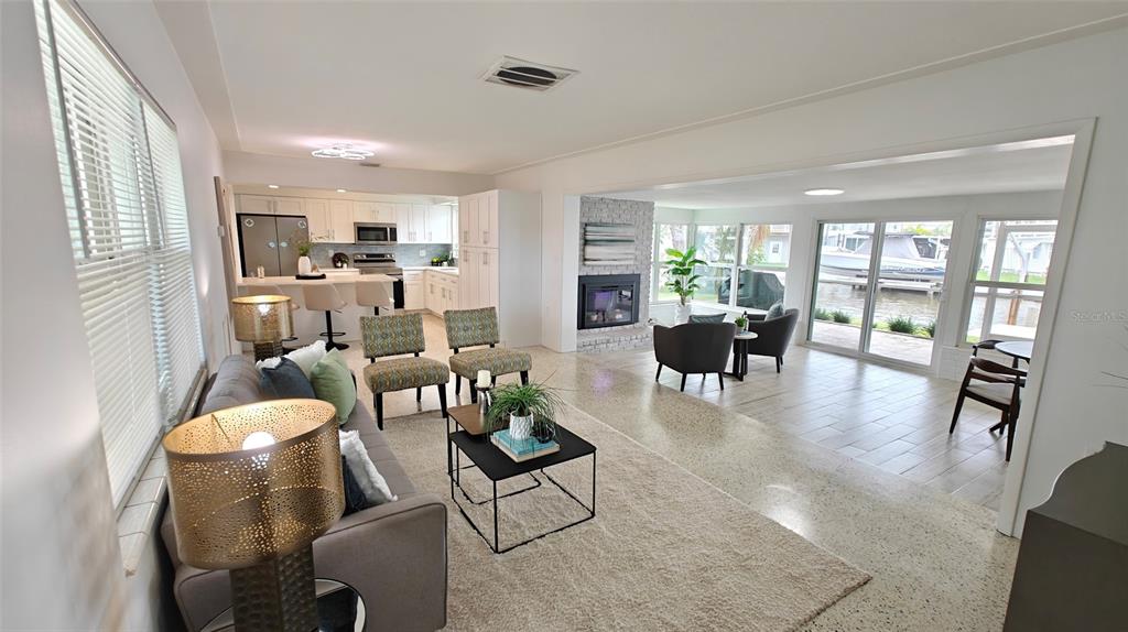 An open-concept living room and kitchen feature a fireplace, tile flooring, and sliding glass doors — 8521 42ND AVENUE N, ST PETERSBURG, FL