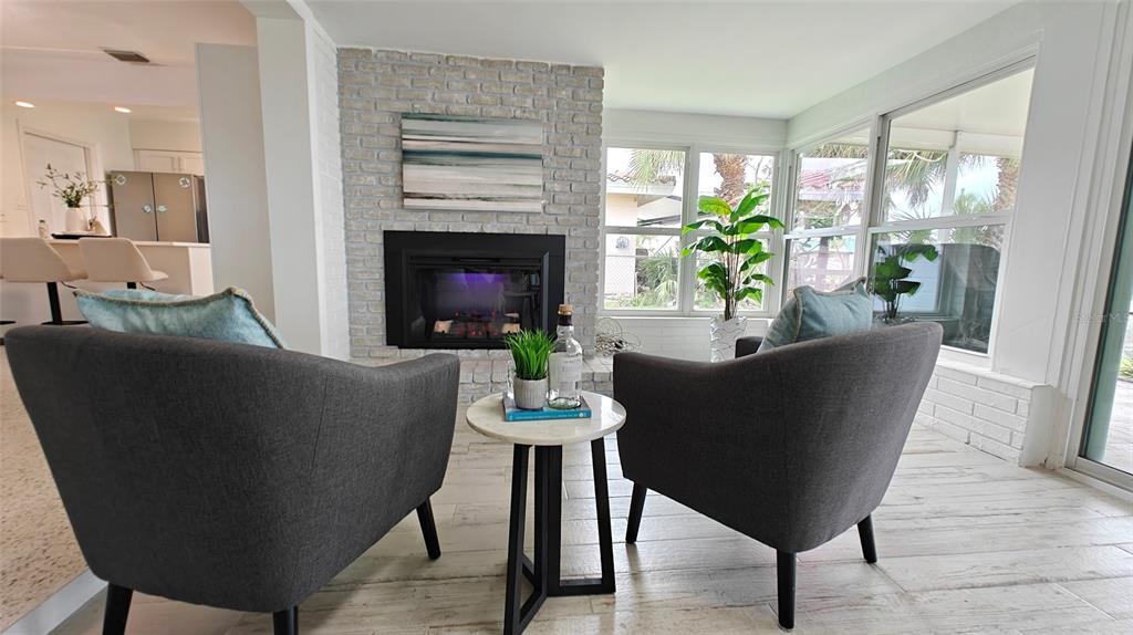 A sunroom features a white brick fireplace, two gray armchairs, and a small round table — 8521 42ND AVENUE N, ST PETERSBURG, FL