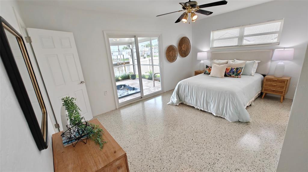 A bedroom with a bed, terrazzo flooring, and sliding glass doors leading to a patio — 8521 42ND AVENUE N, ST PETERSBURG, FL
