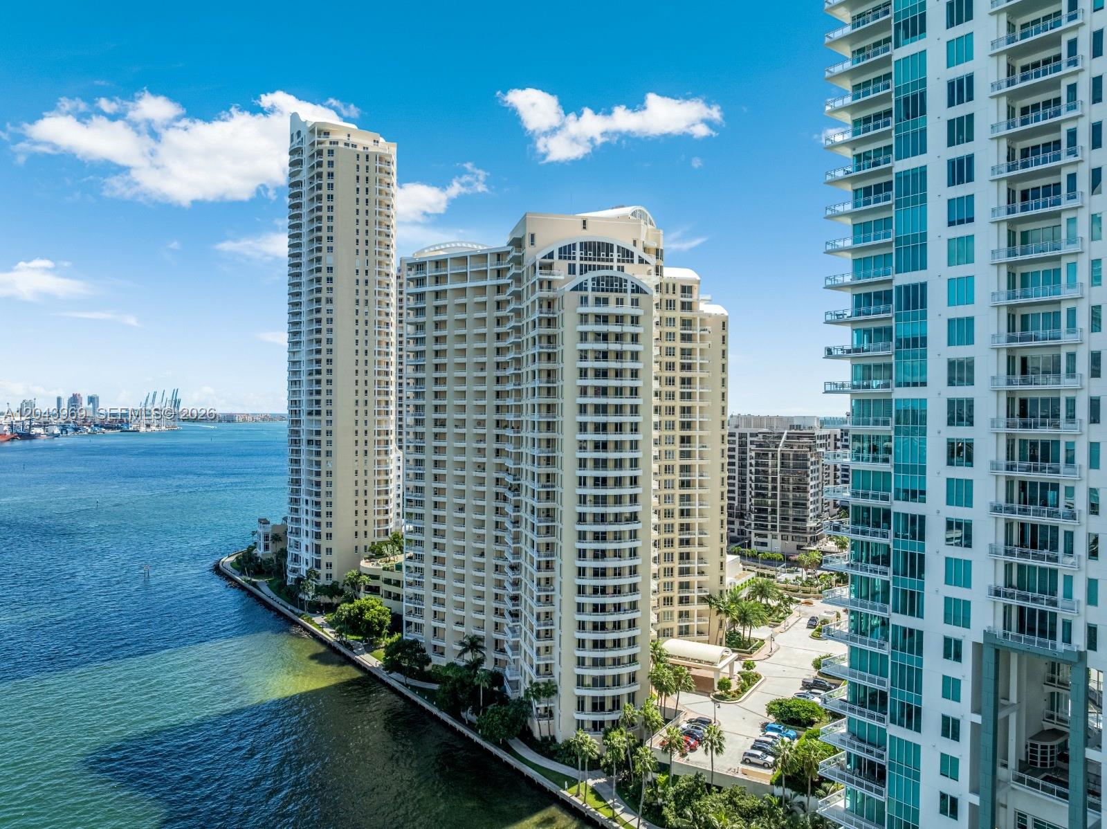 An aerial view shows three tall residential towers situated along a waterfront with a parking lot — 888 Brickell Key Dr # 2610, Miami FL 33131, MIAMI, FL